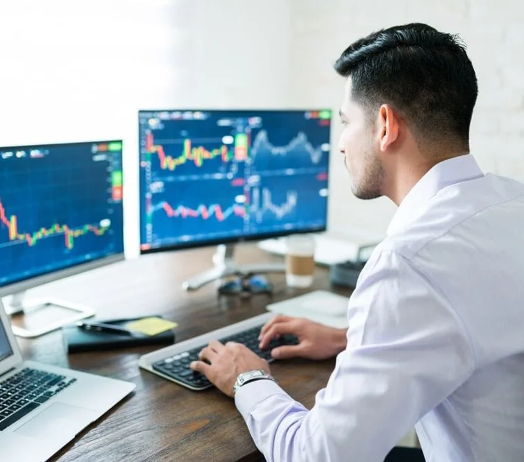 Trader étudiant les graphiques en temps réel sur plusieurs écrans